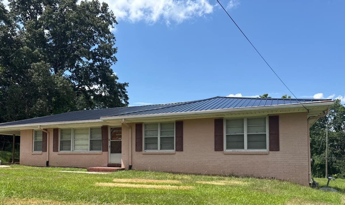 Brick ranch home in Gardendale, AL under a new charcoal ribbed metal roof, carport at left