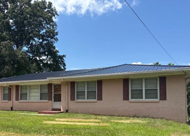 Brick ranch home in Gardendale, AL under a new charcoal ribbed metal roof, carport at left