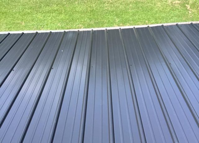 Straight-on view of charcoal ribbed panels, rows of dark screws and the pale lower edge