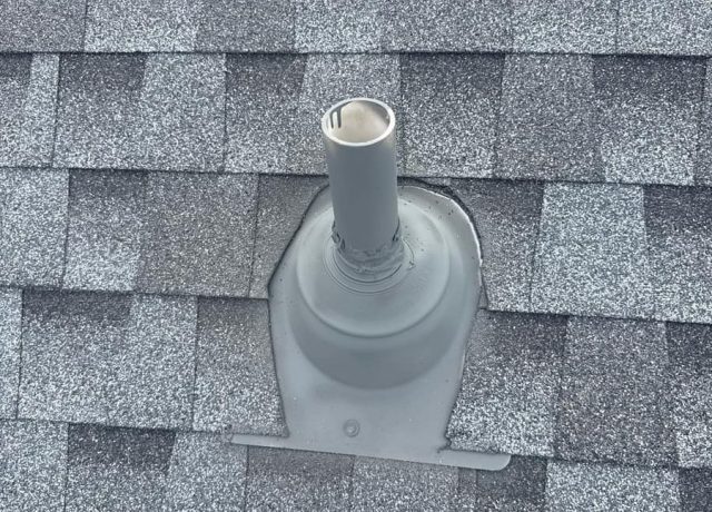Gray pipe boot with a sealed collar and fastener set into the shingles