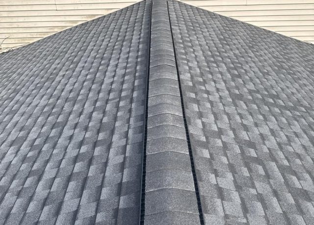 Capped ridge with a vent strip on each side rising to a peak at cream siding